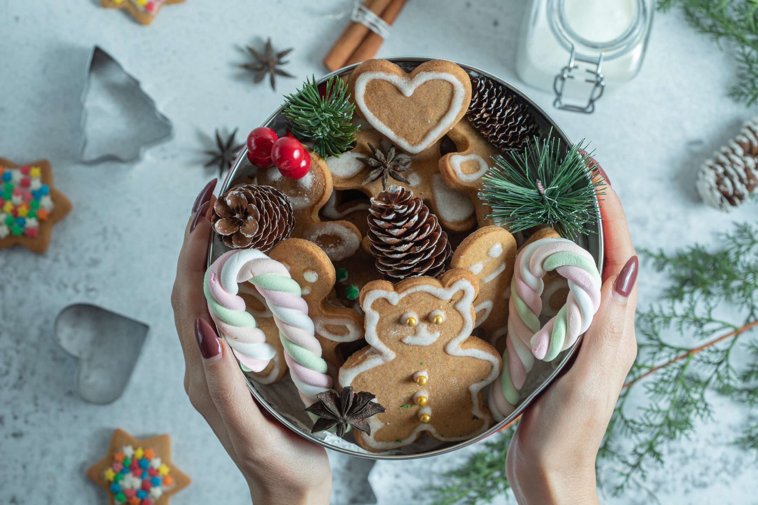 Female holding crockery on hand. Crockery full of Christmas cookies and decorations